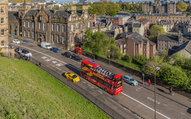Edinburgh cityscape with a red double-decker bus on a Hop on Hop off Bus Tour.