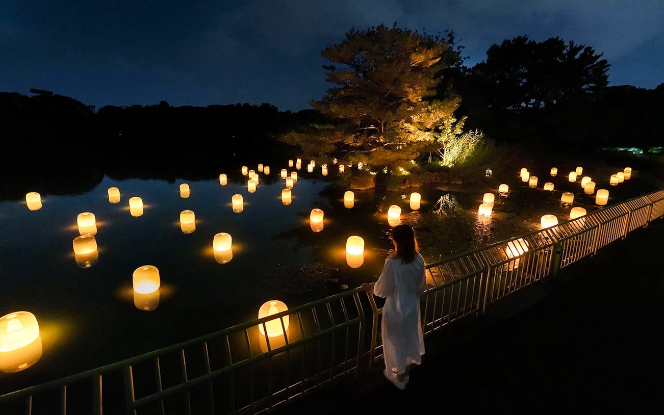 Glowing spheres in a forest setting at teamLab Botanical Garden Osaka art installation.