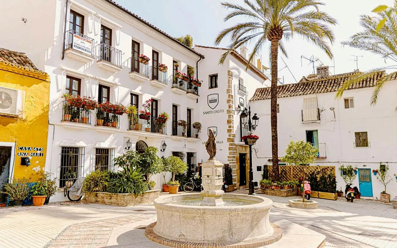 Plaza with fountain and traditional buildings in Marbella, part of the guided day trip including Colomares Castle.
