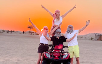 Group enjoying quad bike ride at sunset in Abu Dhabi desert.