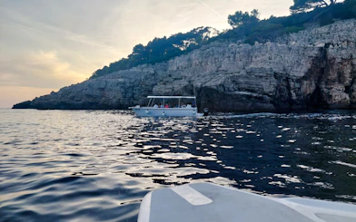 Boat tour along rocky coastline at sunset, Dubrovnik.