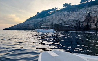 Boat tour along rocky coastline at sunset, Dubrovnik.