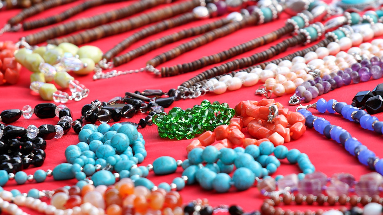 Colorful gemstone necklaces displayed on a red cloth