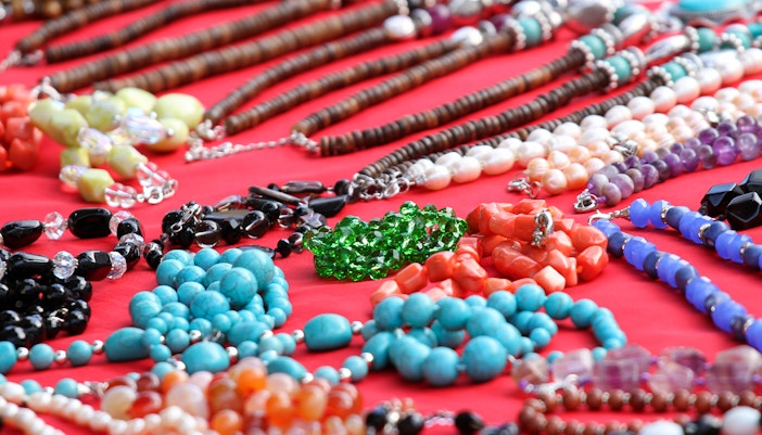 Colorful gemstone necklaces displayed on a red cloth