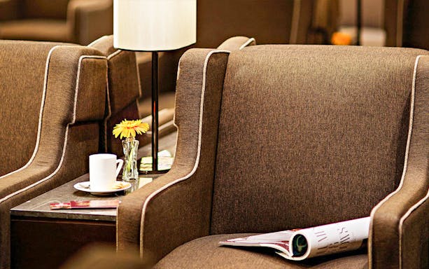 Plaza Premium First lounge seating with coffee and magazine on side table.