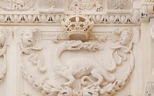 Stone relief of a dragon and crown at Cité internationale de la langue française.