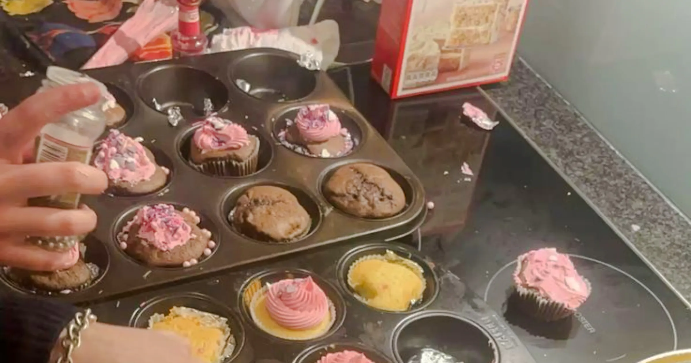 Cupcakes being decorated with pink frosting and sprinkles at a workshop in Essaouira.