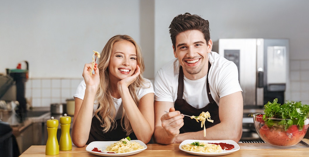Young friends making pasta together in a kitchen, showcasing a fun cooking class experience.