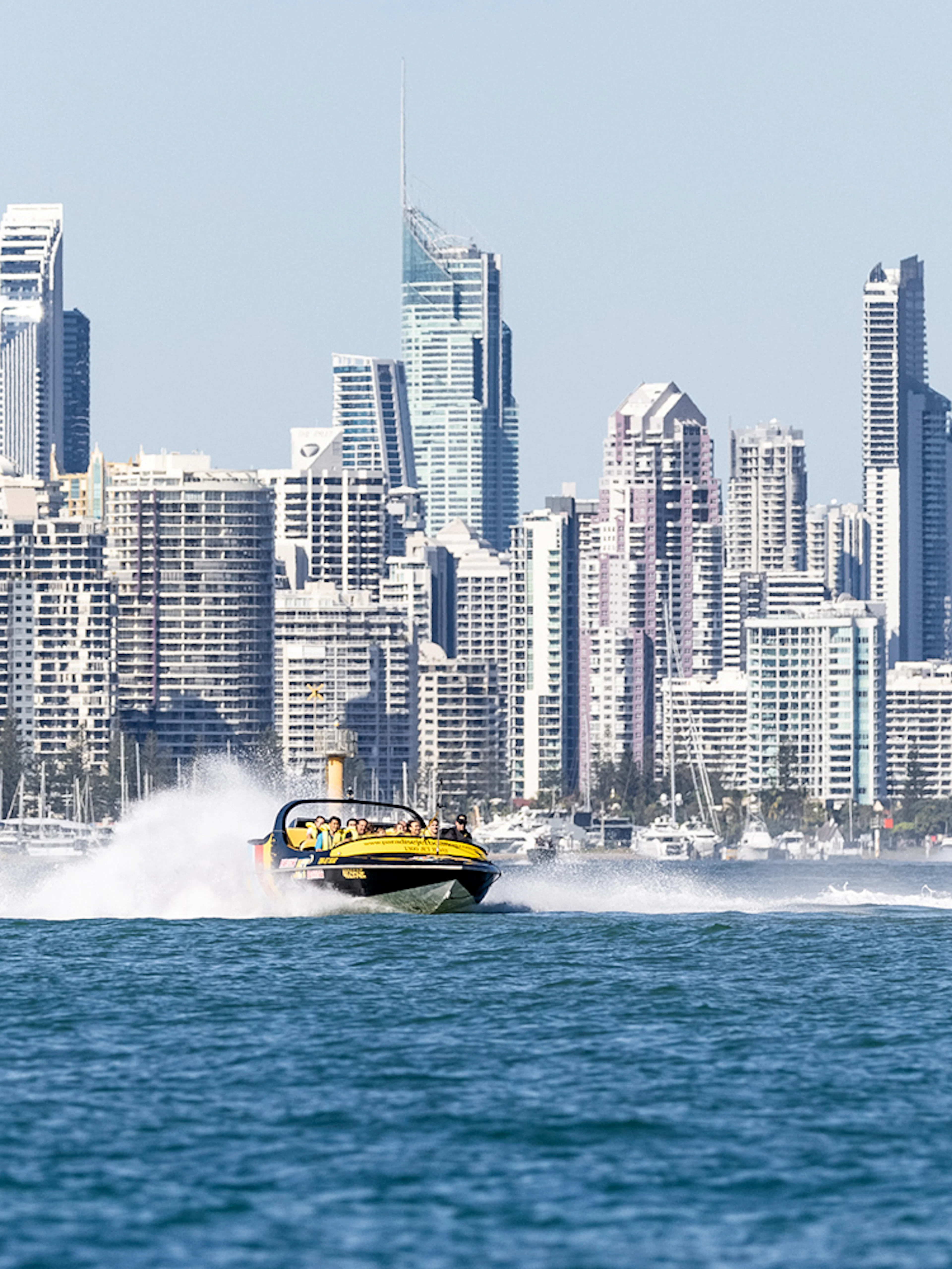 Jet boat speeding on water with city skyline in the background, part of Jet Boat Adventure Ride & Aquaduck Safari Combo.