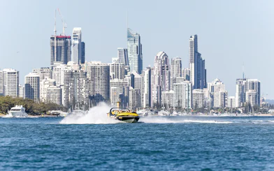 Jet boat speeding on water with city skyline in the background, part of Jet Boat Adventure Ride & Aquaduck Safari Combo.