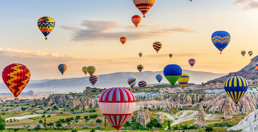 Classic car tour in Cappadocia with hot air balloons in the background.