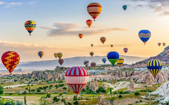 Classic car tour in Cappadocia with hot air balloons in the background.