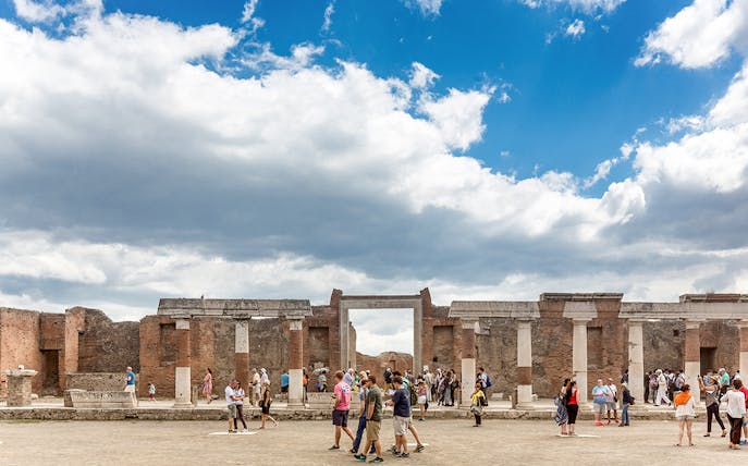 Tourists exploring ancient ruins at Pompeii archaeological site.