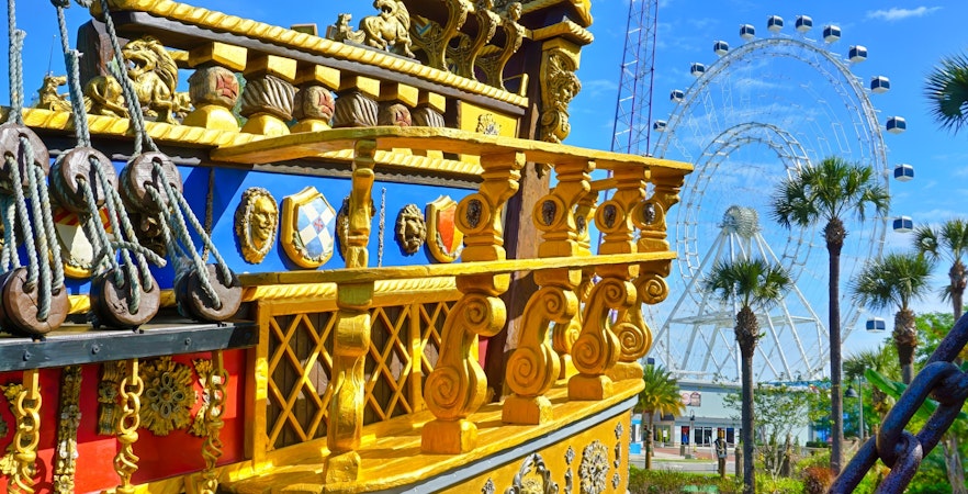 Pirate ship detail at Pirate's Cove Adventure Golf with Ferris wheel in the background.