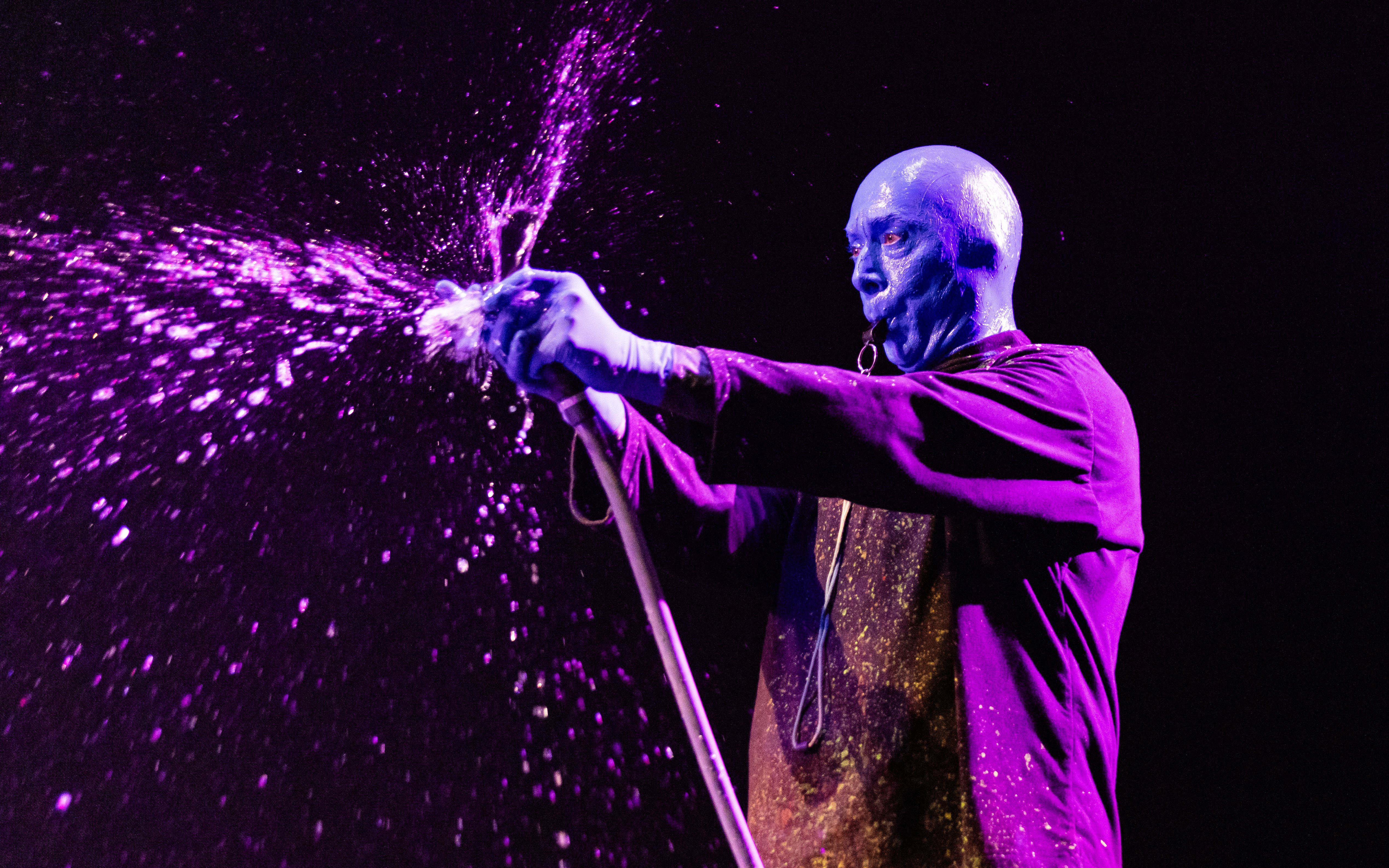 Blue Man Group performer spraying paint during show in Orlando.