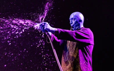 Blue Man Group performer spraying paint during show in Orlando.