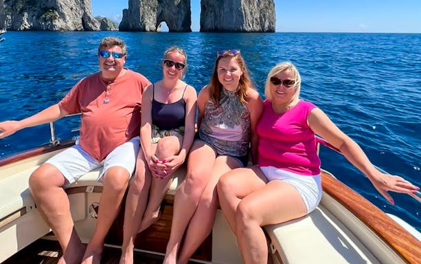 Group enjoying a boat tour near Faraglioni rocks, Capri.