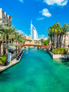 Burj Al Arab with surrounding palm trees and waterway in Dubai.