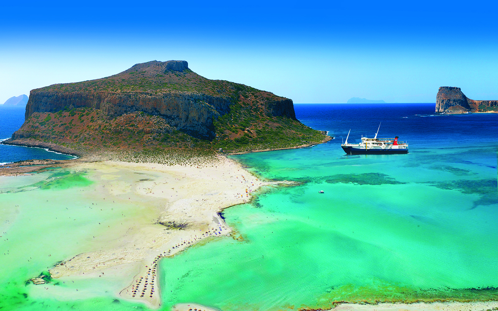 Cruise ship near Balos Island's turquoise waters and sandy beach, Greece.
