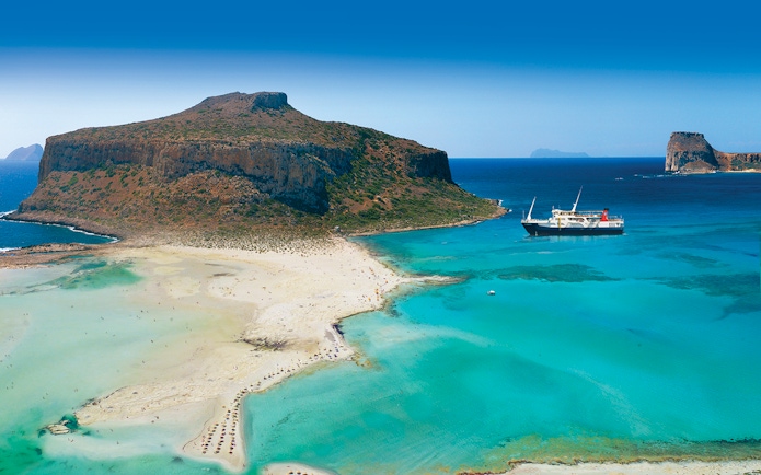 Cruise ship near Balos Island's turquoise waters and sandy beach, Greece.