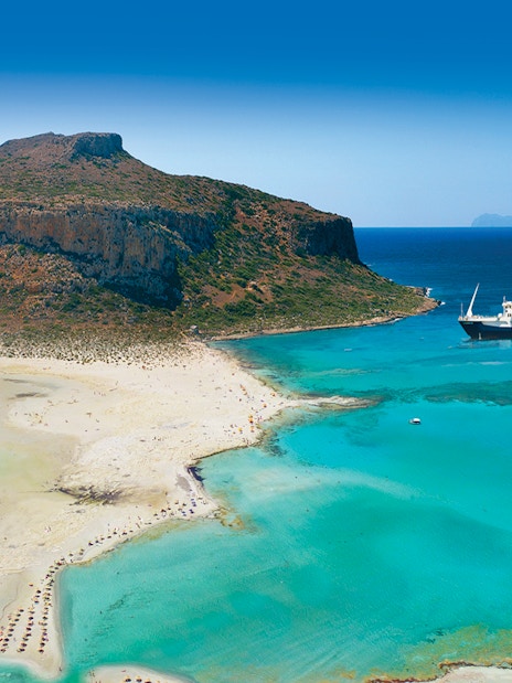 Cruise ship near Balos Island's turquoise waters and sandy beach, Greece.