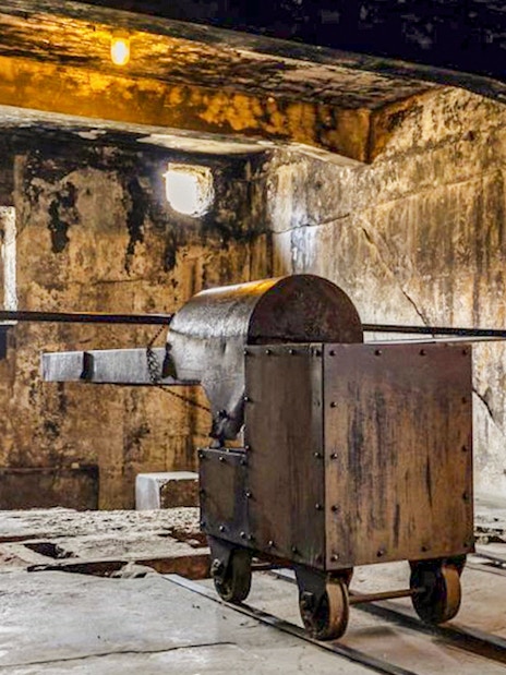 Crematorium interior at Auschwitz-Birkenau with metal cart on tracks.