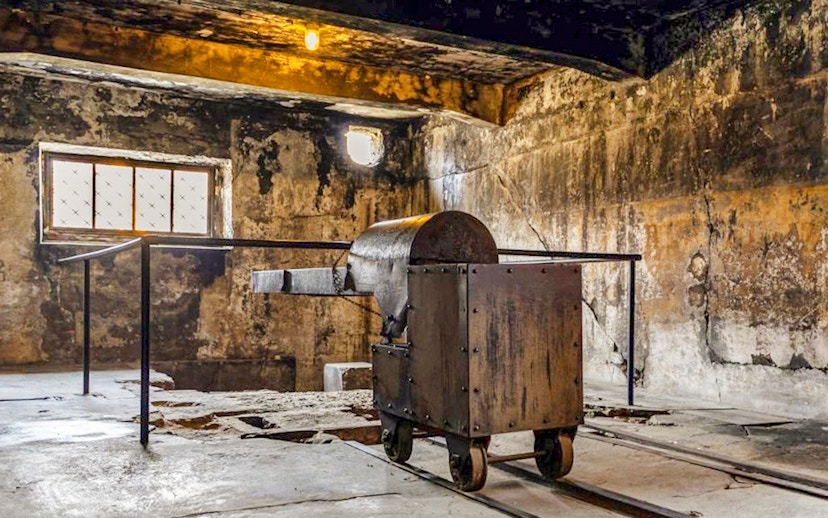 Crematorium interior at Auschwitz-Birkenau with metal cart on tracks.