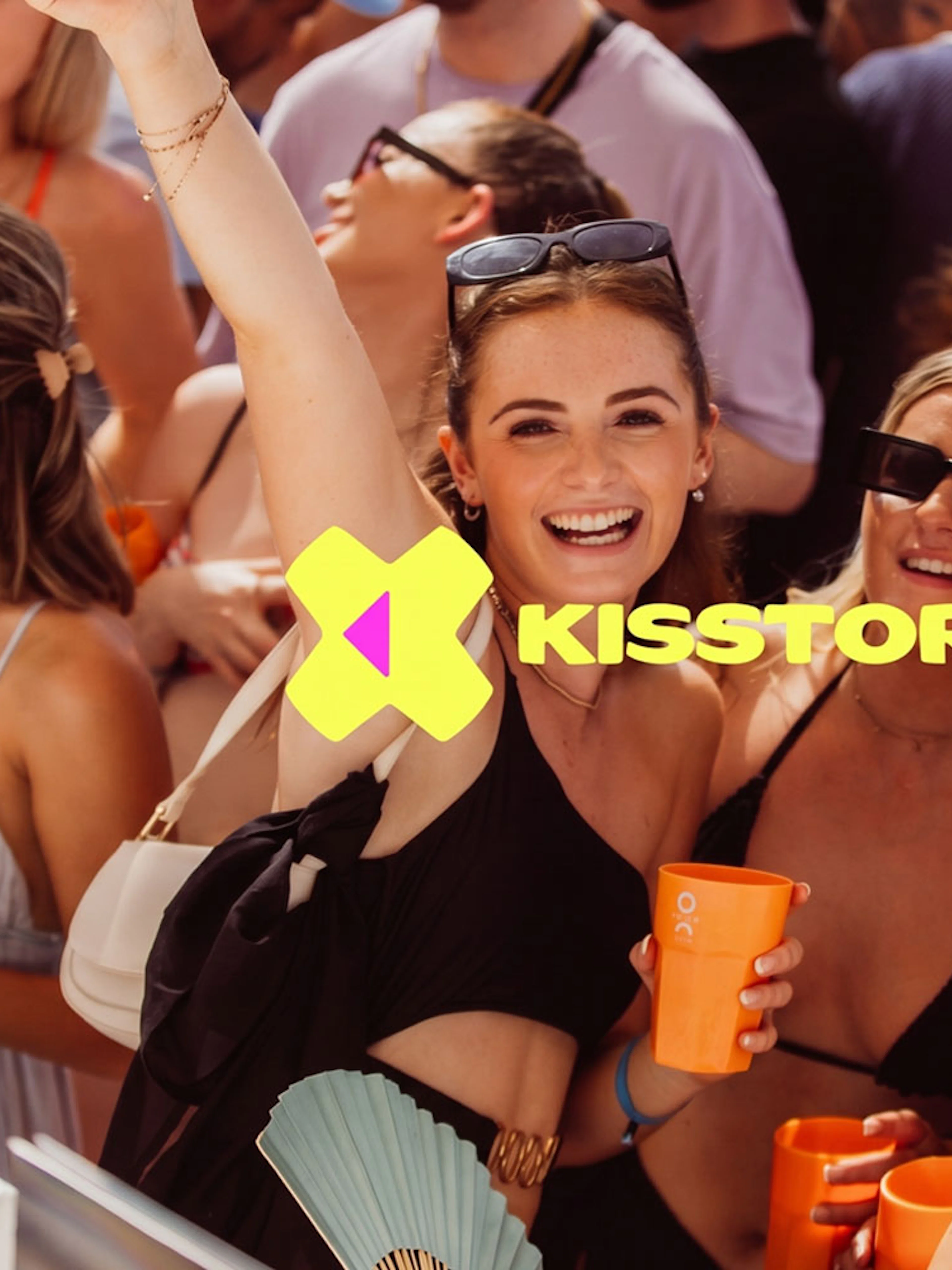 Partygoers enjoying Kisstory event at O Beach Ibiza with drinks and music.