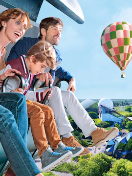 Family enjoying a ride at Futuroscope with a hot air balloon in the background.
