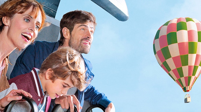 Family enjoying a ride at Futuroscope with a hot air balloon in the background.