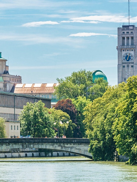 Munich cityscape with Isar River, bridge, and historic buildings in the inner area.