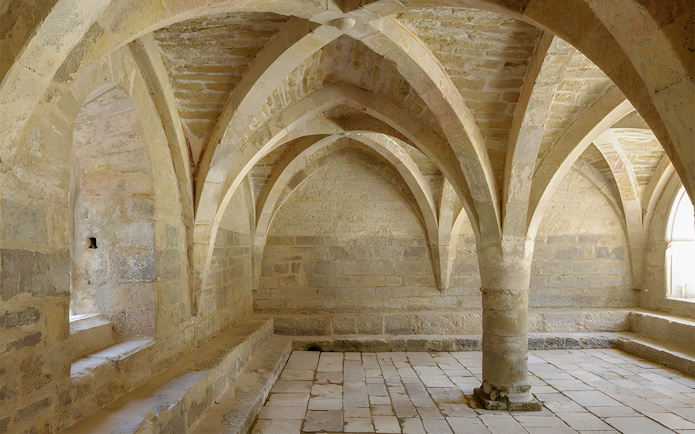 Beaulieu-en-Rouergue Abbey stone vaulted interior with arches and columns.