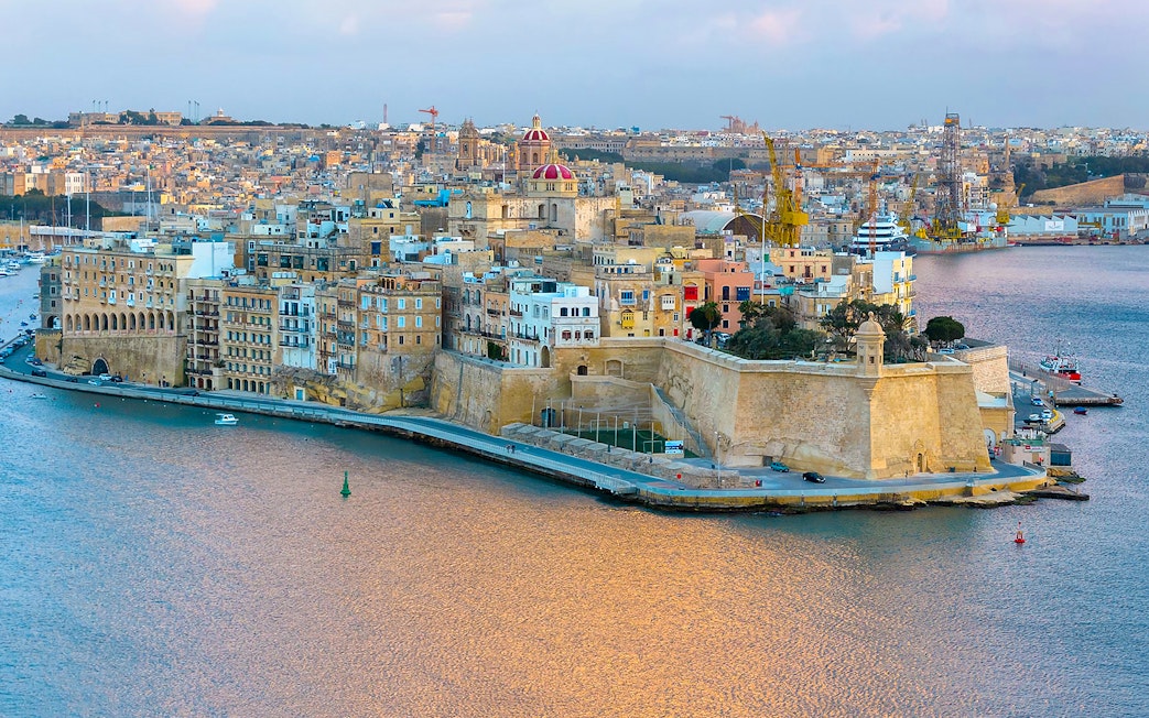 Valletta skyline and harbor view from Sliema, featuring historic buildings and waterfront.