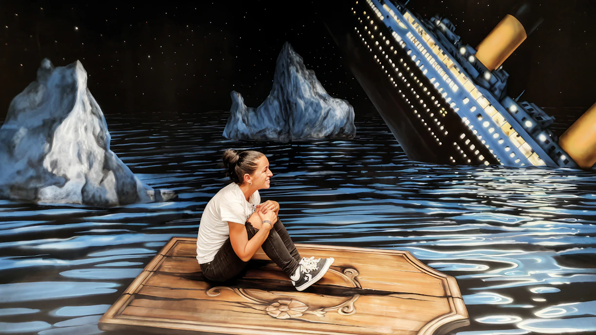 Person sitting on a wooden plank in front of a sinking ship illusion at the Museum of Fantastic Illusions.