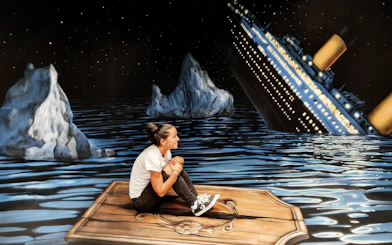 Person sitting on a wooden plank in front of a sinking ship illusion at the Museum of Fantastic Illusions.