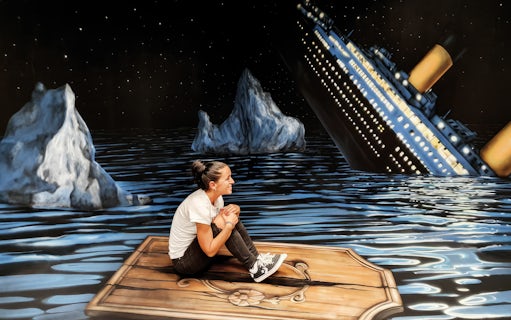 Person sitting on a wooden plank in front of a sinking ship illusion at the Museum of Fantastic Illusions.