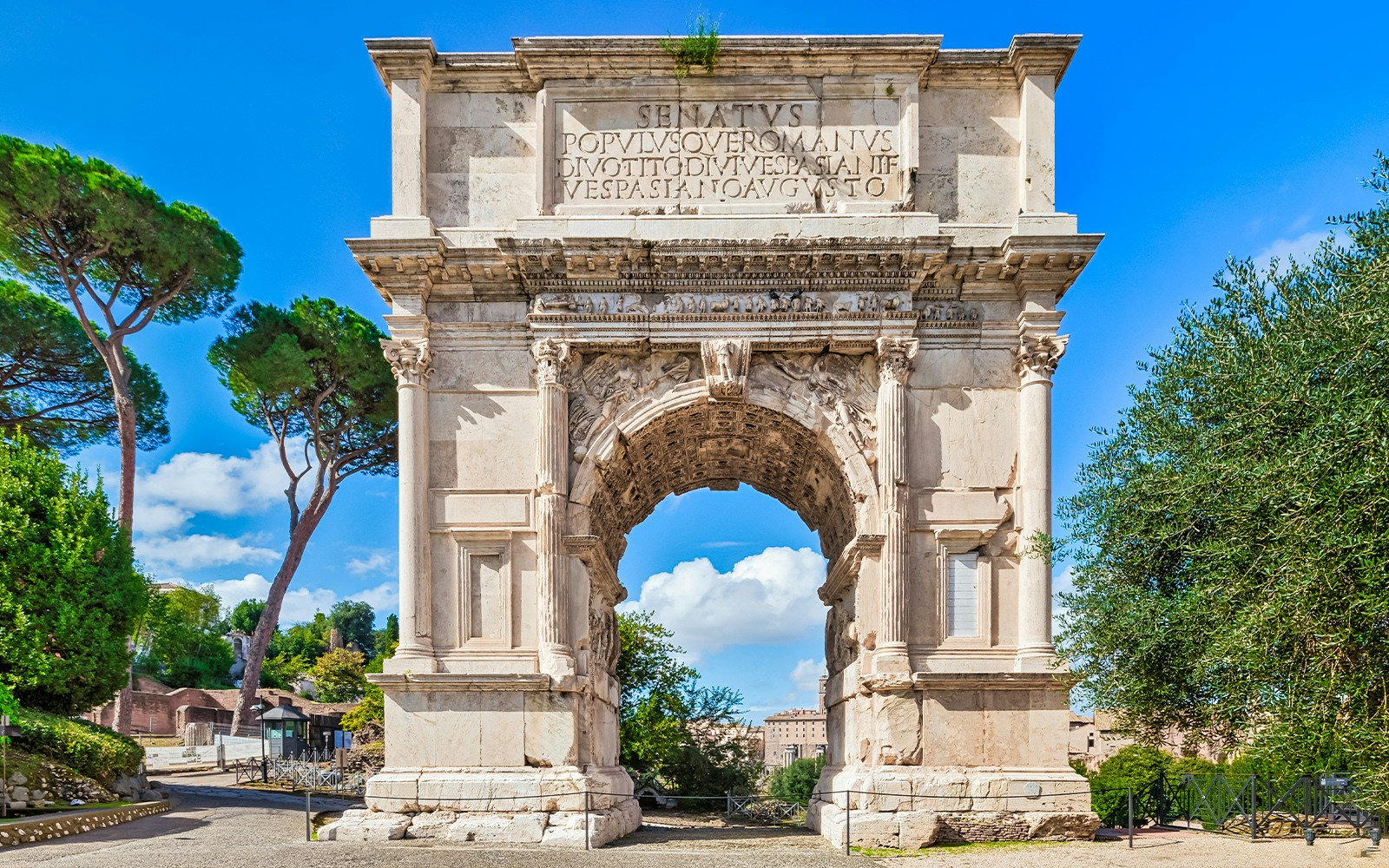 Arch of Titus in the Roman Forum, Rome, with detailed carvings and surrounding greenery.