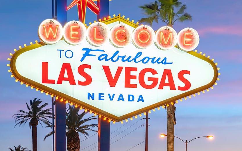Las Vegas iconic sign with tourists taking photos at sunset.