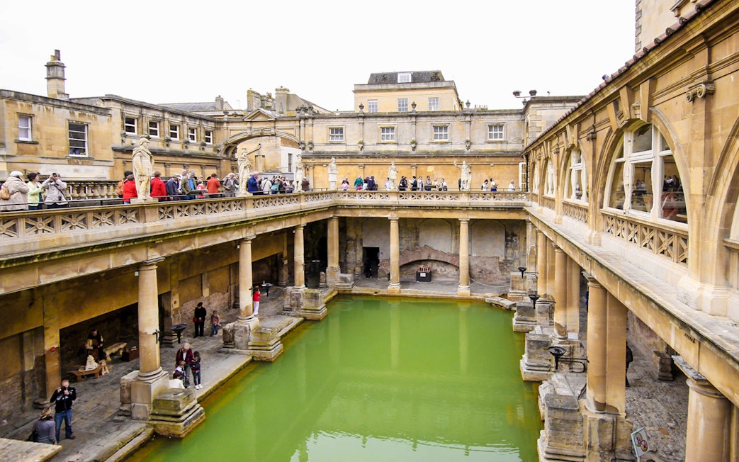 Roman Baths in Bath, England, with tourists exploring the ancient site.
