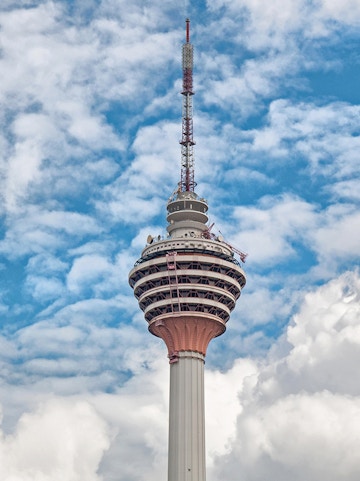 Television tower against a blue sky with clouds.