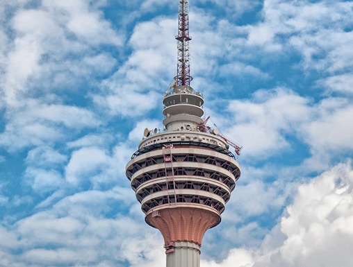 Television tower against a blue sky with clouds.