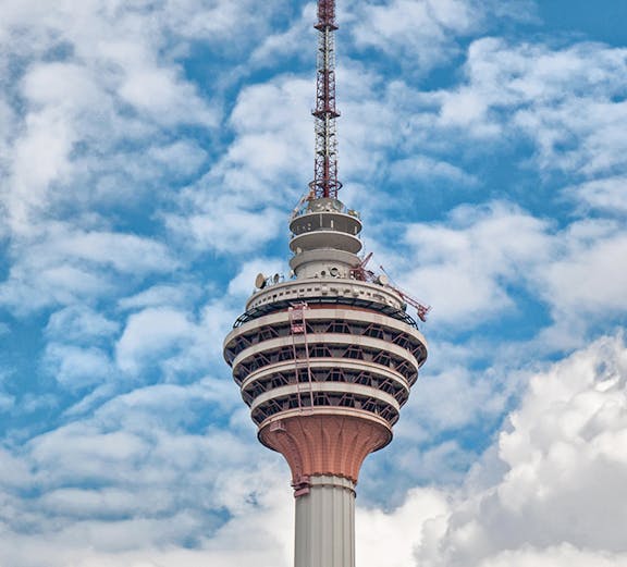 Television tower against a blue sky with clouds.