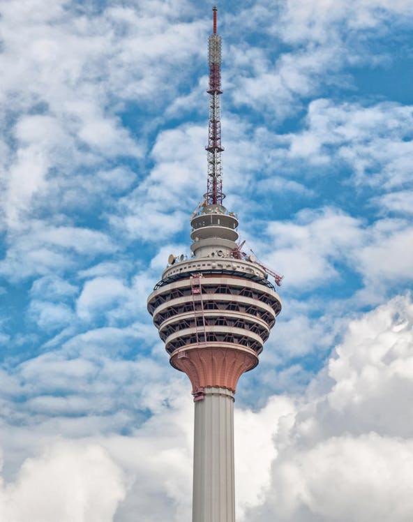 Television tower against a blue sky with clouds.