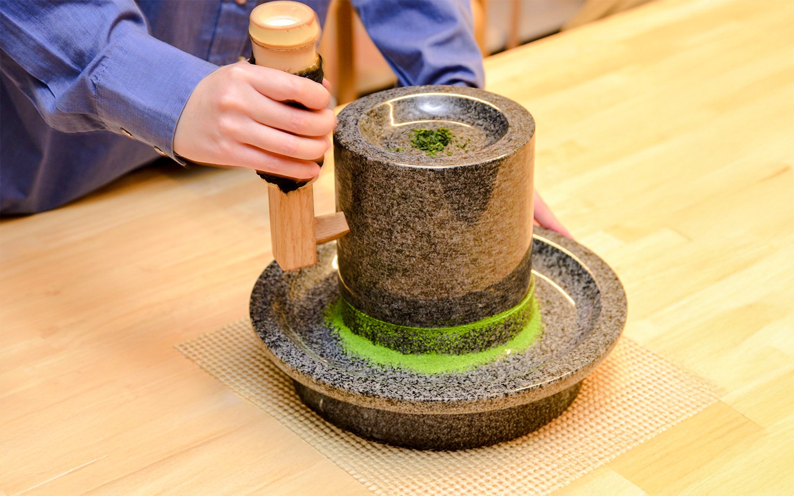Grinding tencha leaves into matcha powder with a granite stone mill.