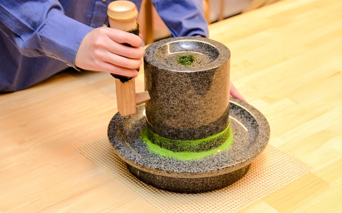 Grinding tencha leaves into matcha powder with a granite stone mill.