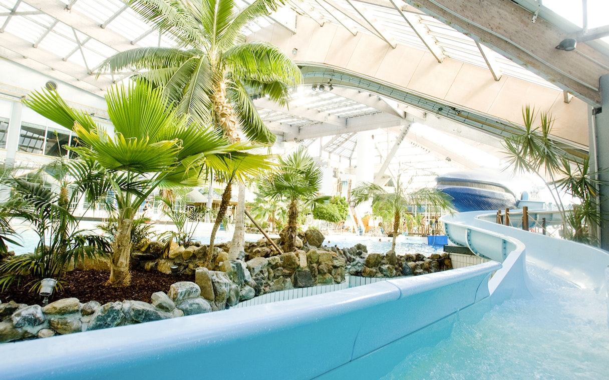 Indoor water slide and tropical plants at Aquaboulevard de Paris.
