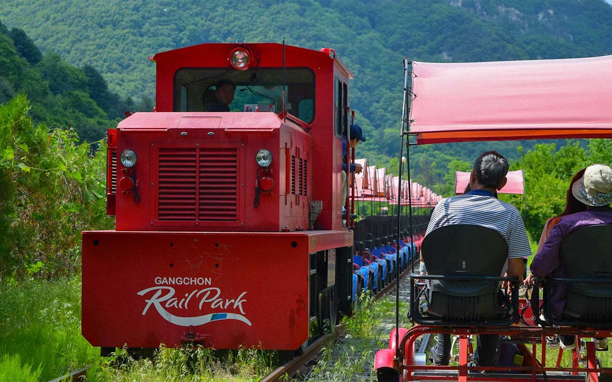 Gangchon Rail Park ride with passengers on a rail bike, surrounded by lush greenery in Gapyeong.