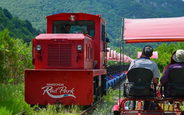 Gangchon Rail Park ride with passengers on a rail bike, surrounded by lush greenery in Gapyeong.