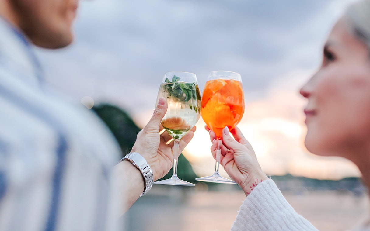 Couple toasting with Aperol on Budapest Danube River nighttime cruise.