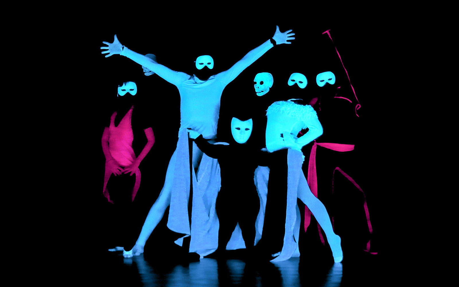 Performers in masks at a black light theatre show, Prague.